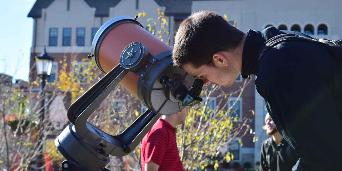 A student looks through a telescope in Astronomy class