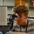 A student looks through an eyepiece in a lab